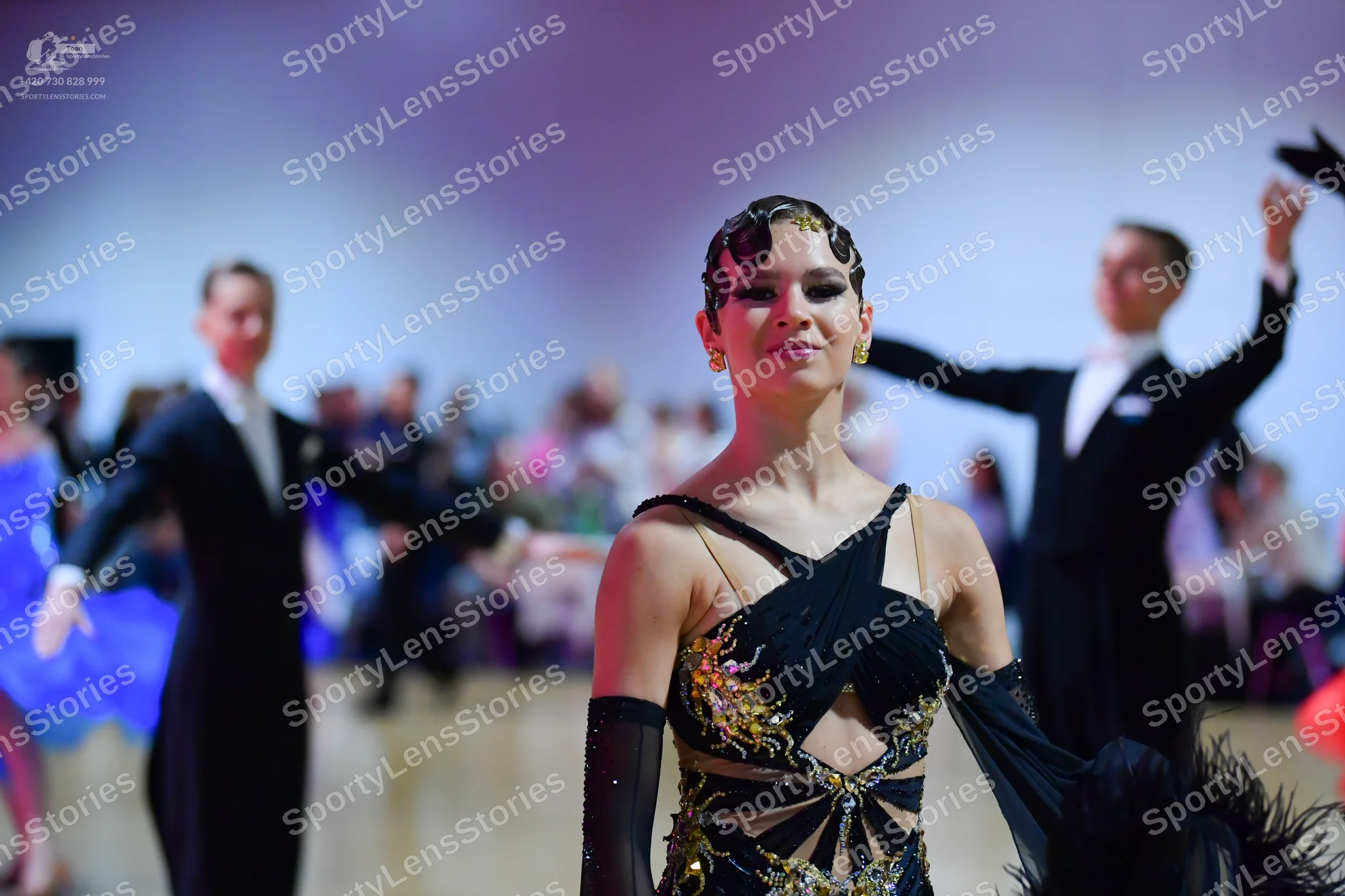 Dancesport competitor: Female dancer in center: black latin dress with gold sequin embroidery and cutou