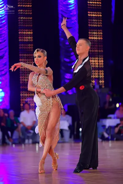 Dancesport competitor: Female dancer: gold sequined Latin dress with white fabric accents