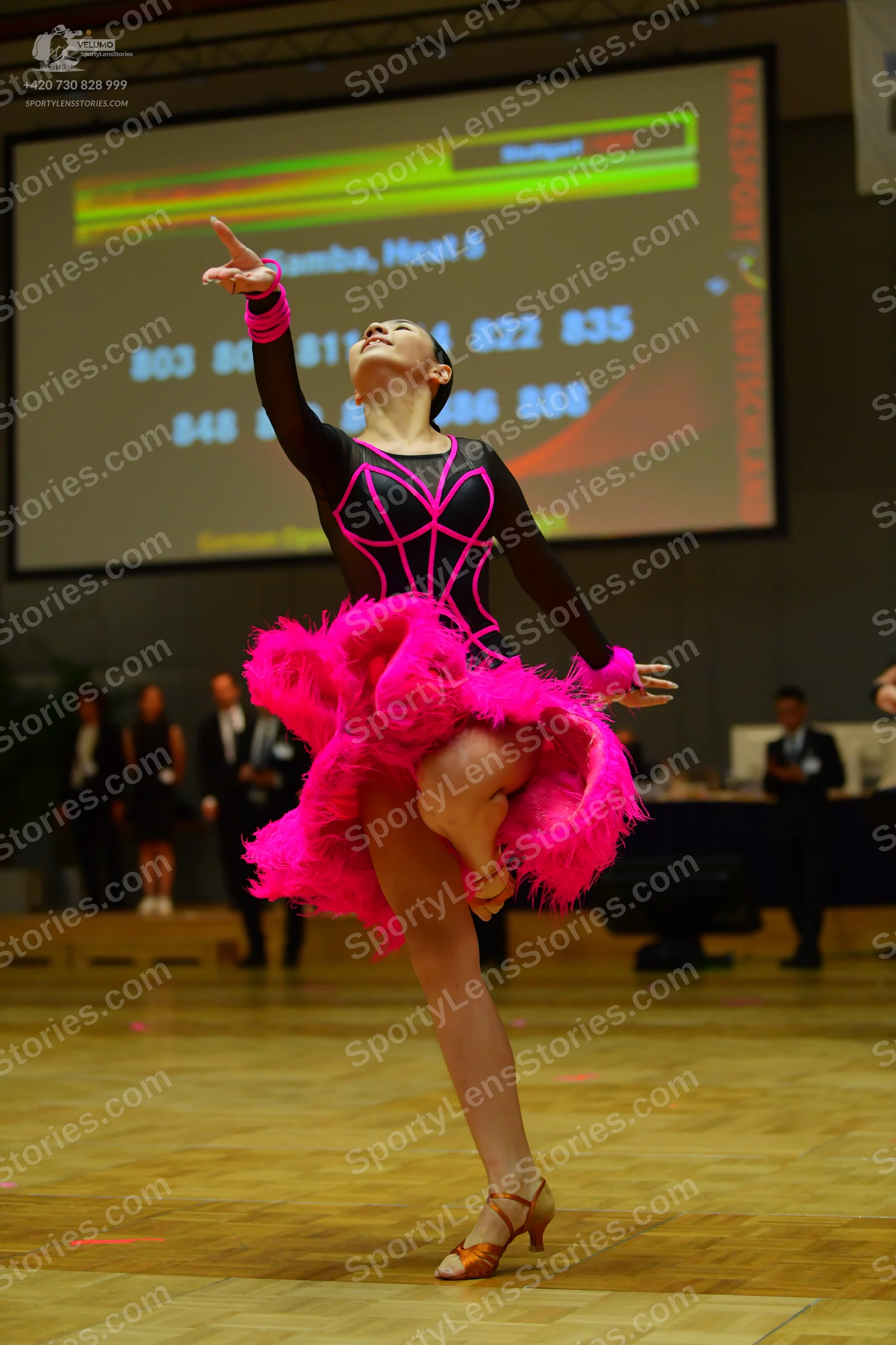 Dancesport competitor: Female dancer: black long-sleeved latin dress with bright pink piping and a volu