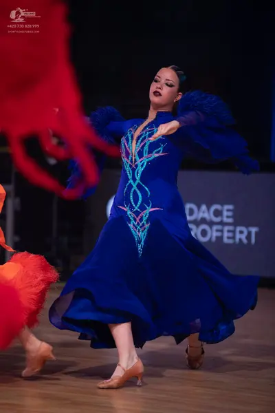 Dancesport competitor: Female dancer in center: royal blue ballroom dress with voluminous, ruffled slee