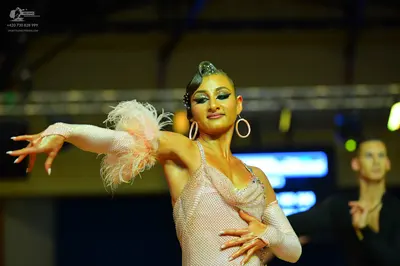Dancesport competitor: Female dancer: light pink sequined Latin dress with long sheer sleeves and feath