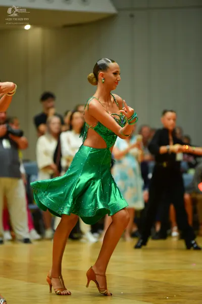 Dancesport competitor: Female dancer: emerald green satin latin dress with thin straps and a flared ski