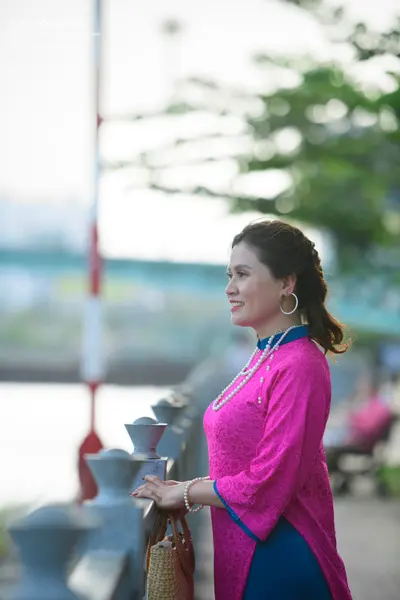 Dancesport competitor: Female dancer: pink patterned long-sleeved top with blue trim, accessorized with