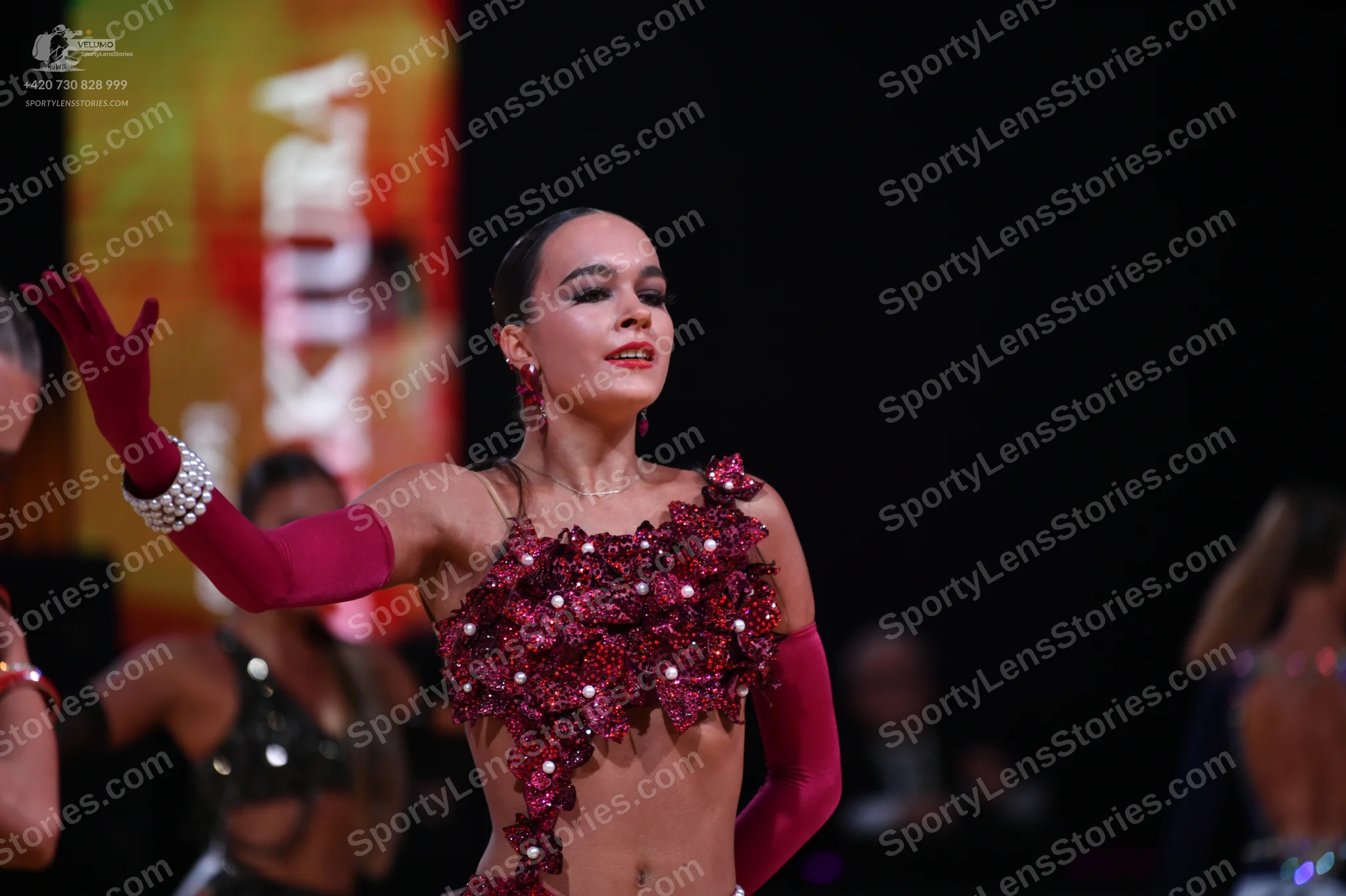 Dancesport competitor: Main female dancer: burgundy Latin costume featuring a cropped top embellished w