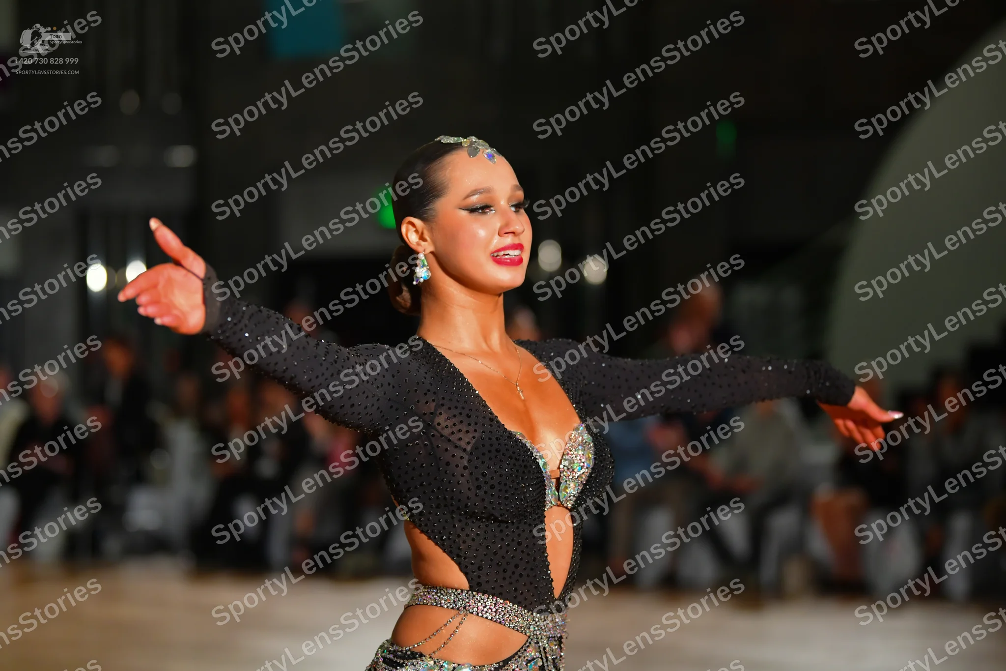 Dancesport competitor: Female dancer: black, long-sleeved, sheer mesh Latin costume heavily embellished