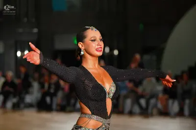 Dancesport competitor: Female dancer: black, long-sleeved, sheer mesh Latin costume heavily embellished