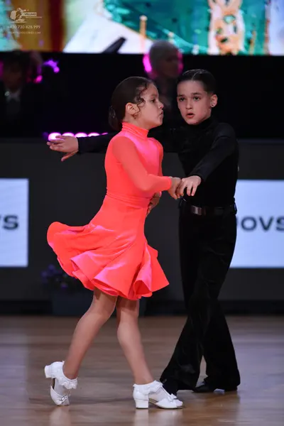 Dancesport competitor: Female dancer: bright coral long-sleeved Latin dance dress with a high neck and 