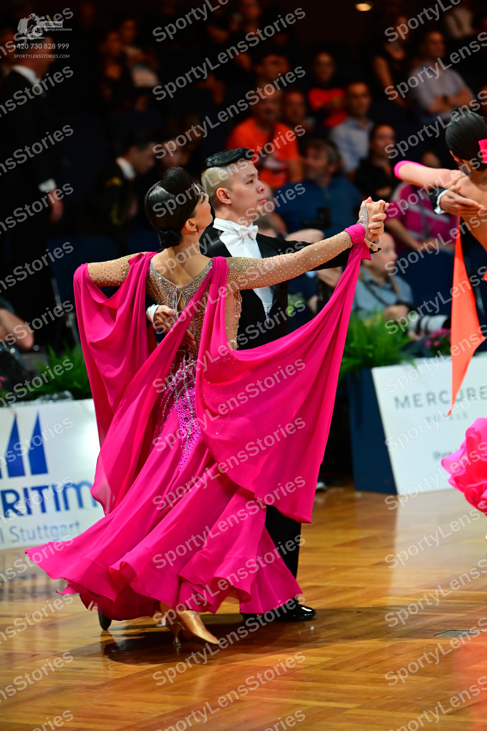 Dancesport competitor: Female dancer: bright pink ballgown with a nude-colored, sequined bodice and a v