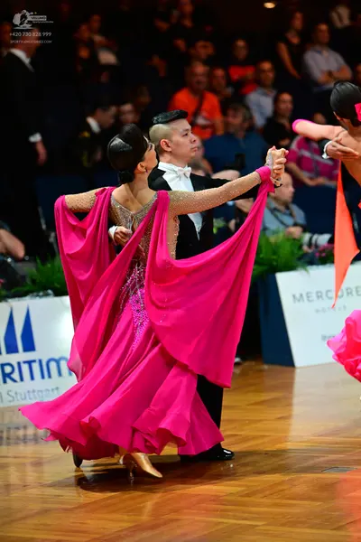 Dancesport competitor: Female dancer: bright pink ballgown with a nude-colored, sequined bodice and a v
