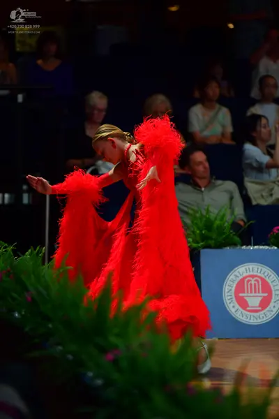Dancesport competitor: Female dancer: red Latin dress with long, voluminous red fringe on the sleeves a