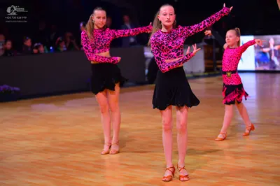 Dancesport competitor: Female dancers: pink and black patterned long-sleeved crop tops with black short