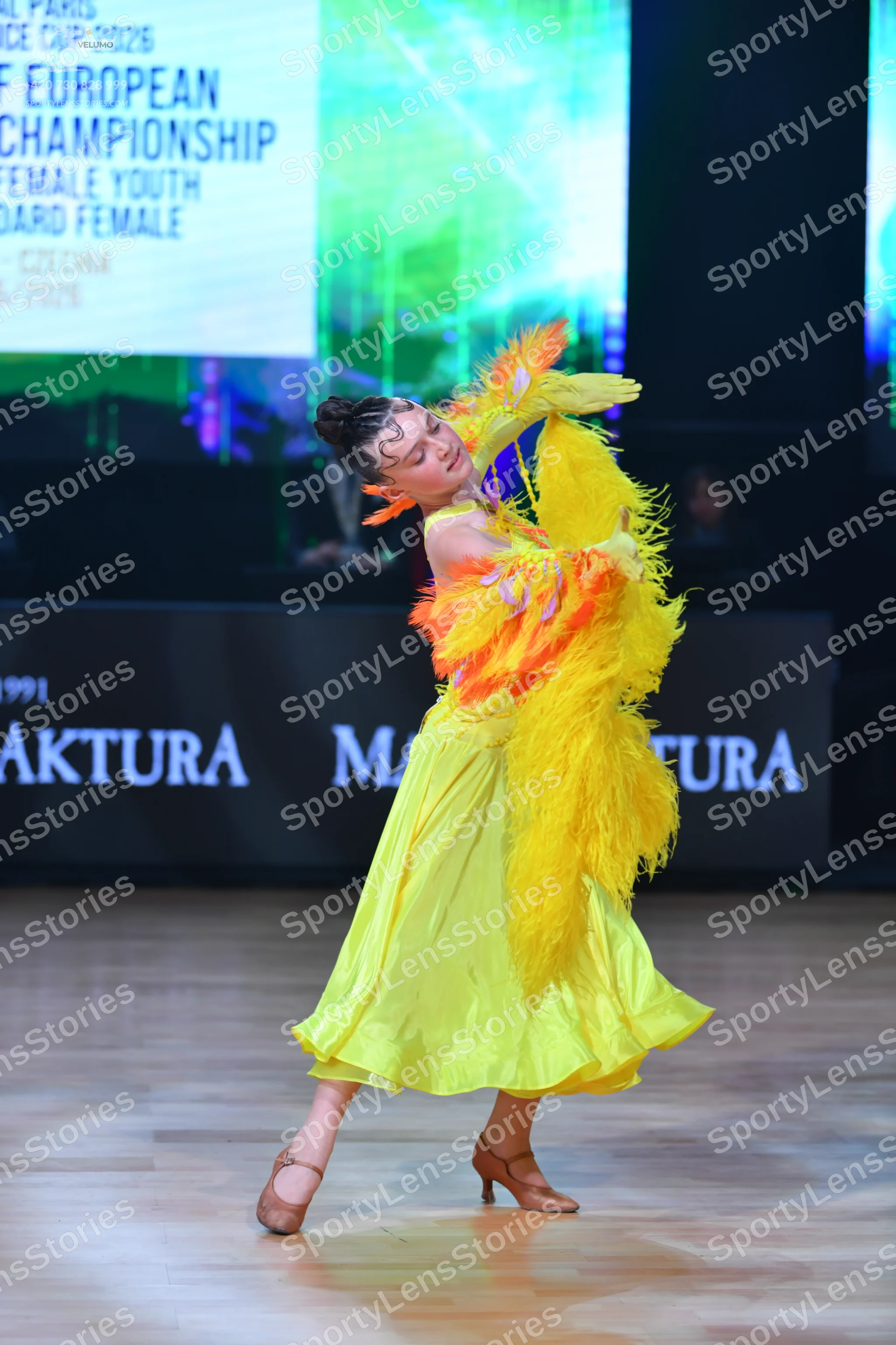Dancesport competitor: Female dancer: bright yellow ballroom dress with a voluminous, smooth-fabric ski