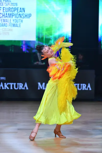 Dancesport competitor: Female dancer: bright yellow ballroom dress with a voluminous, smooth-fabric ski
