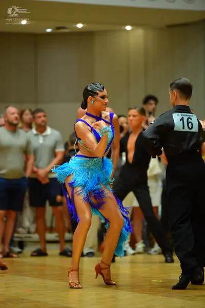 Dancesport competitor: Female dancer: bright blue latin dress with sequins and long fringe