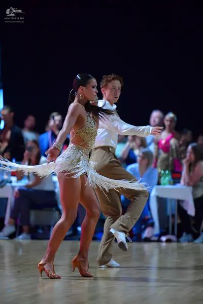 Dancesport competitor: Female dancer: gold sequined latin dress with long white fringe and large hoop e