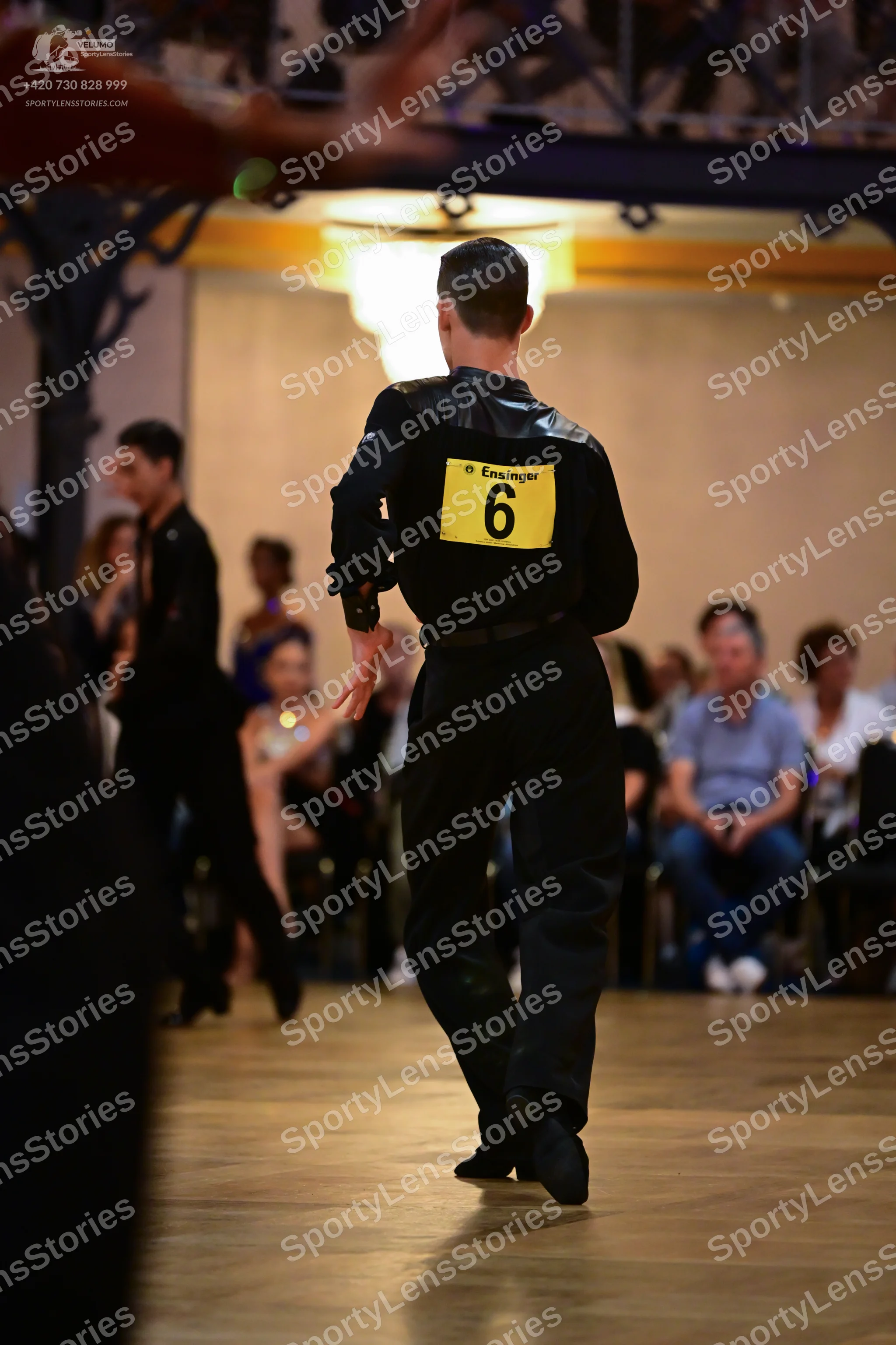 Dancesport competitor: Male dancer (foreground): black long-sleeve shirt with satin-like shoulder panel