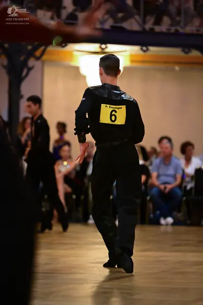 Dancesport competitor: Male dancer (foreground): black long-sleeve shirt with satin-like shoulder panel