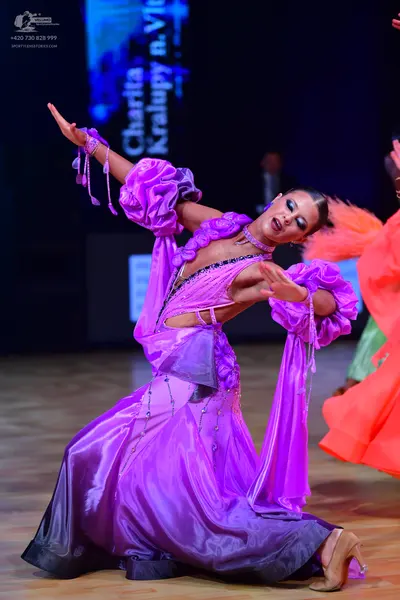 Dancesport competitor: Female dancer: purple and dark purple satin ballgown with large ruffled sleeves 