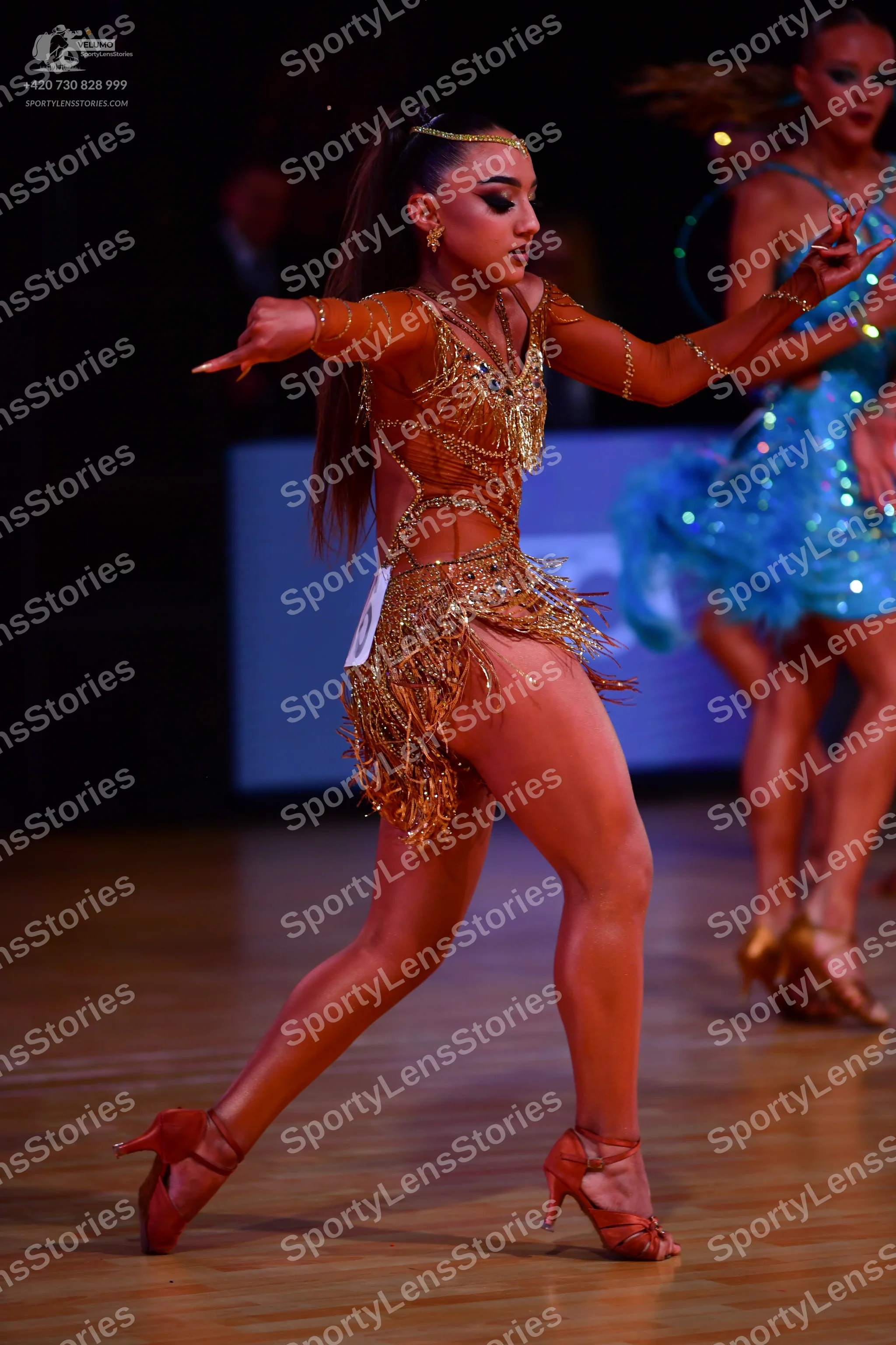 Dancesport competitor: Female dancer: gold Latin dress with sequins and long fringe, featuring long she