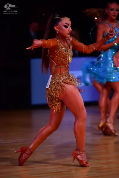 Dancesport competitor: Female dancer: gold Latin dress with sequins and long fringe, featuring long she