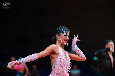 Dancesport competitor: Female dancer: pink Latin dance costume heavily embellished with sequins and rhi