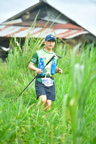 Marathon runner #SB589: Runner 1: green and white jersey, black shorts, blue cap, blue hydration pack