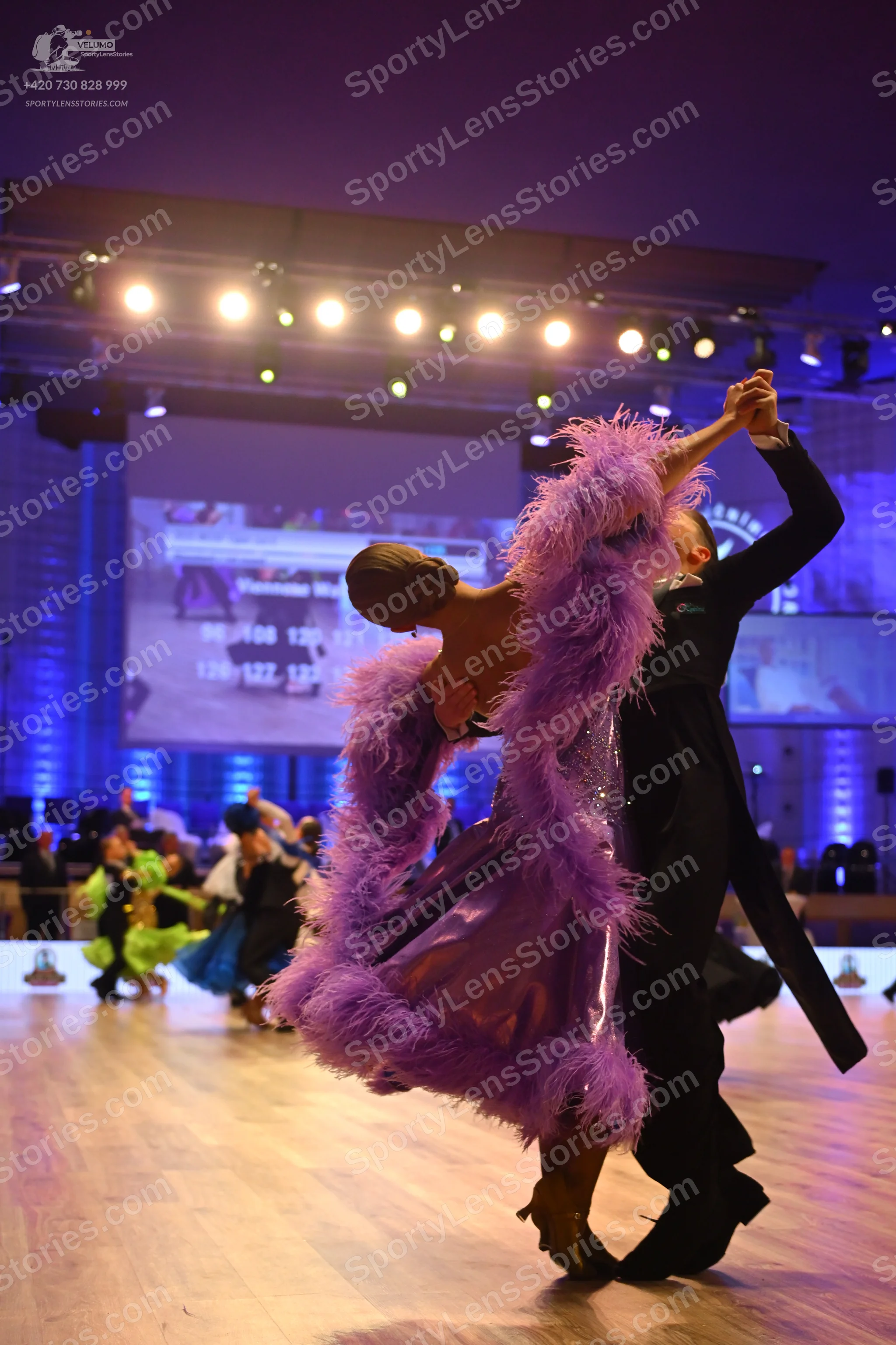 Dancesport competitor: Female dancer: purple satin ballgown with large purple feather trim