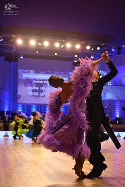 Dancesport competitor: Female dancer: purple satin ballgown with large purple feather trim