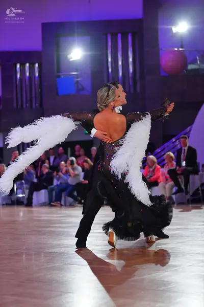 Dancesport competitor: Female dancer: black backless dress with a sequined bodice, sheer long sleeves, 