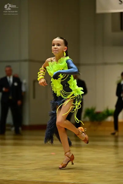 Dancesport competitor: Female dancer: bright lime green/yellow Latin dance dress with a ruffled bodice,