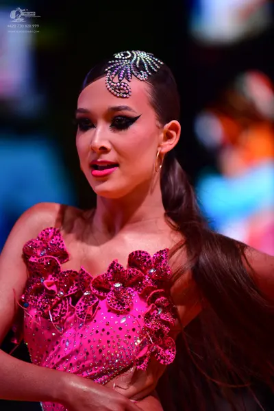 Dancesport competitor: Female dancer: bright pink latin dress with large 3D floral appliqués, heavily e