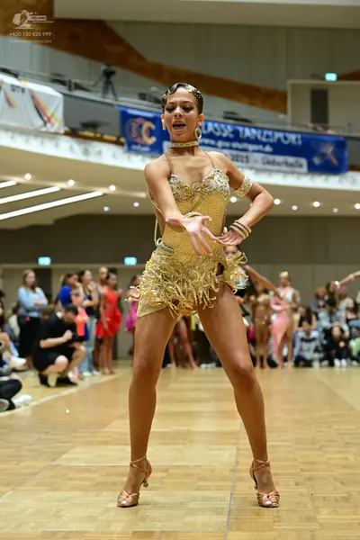 Dancesport competitor: Female dancer in foreground: gold sequin Latin dance dress with fringe and thin 