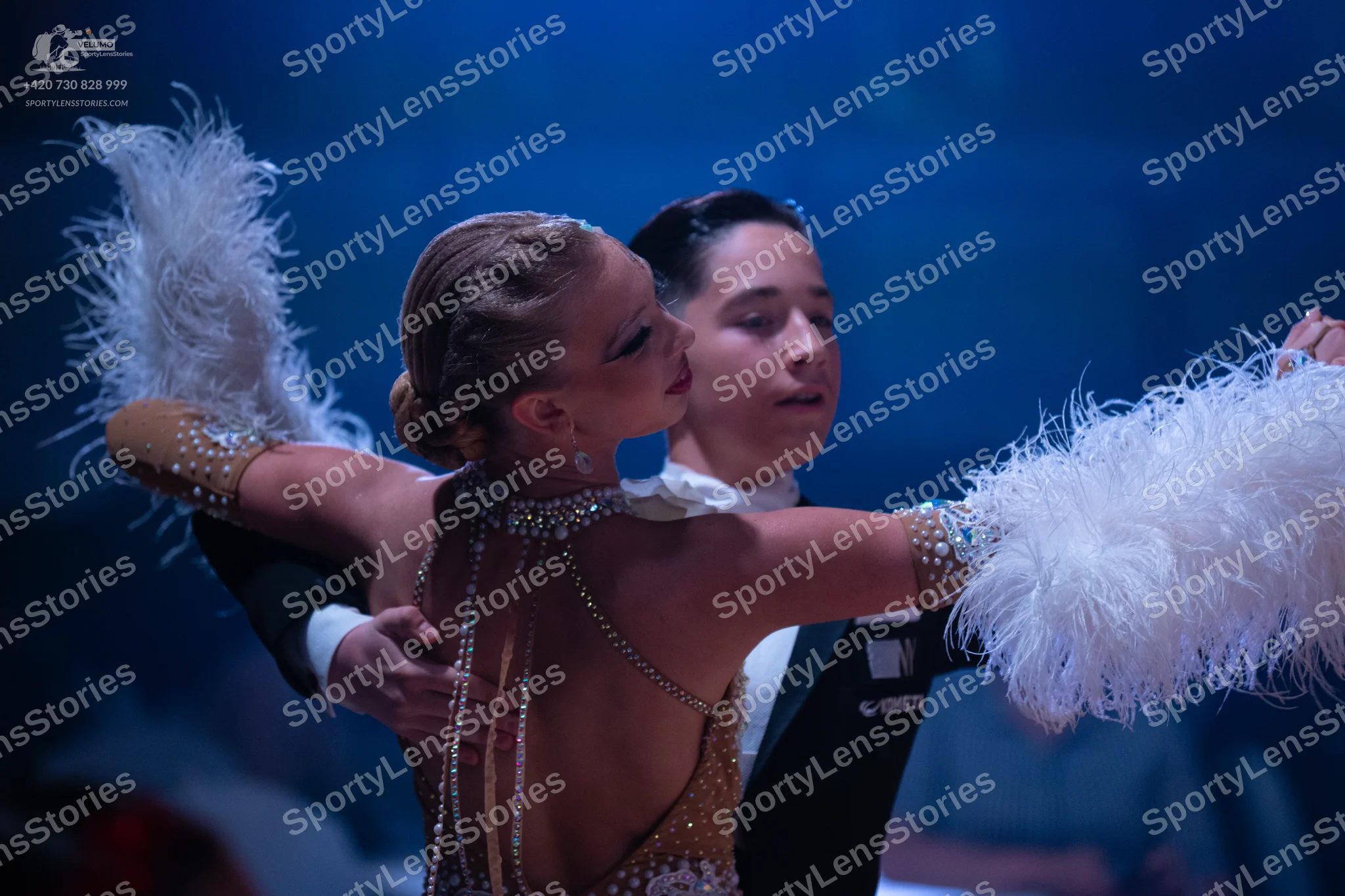 Dancesport competitor: Female dancer: champagne-colored sequined Latin dress with large, white, feather
