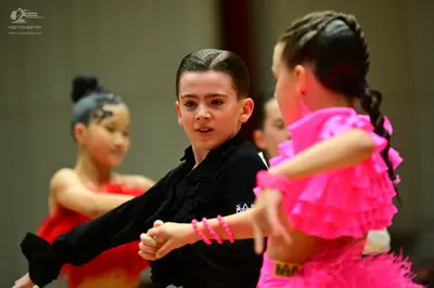 Dancesport competitor: Female dancer (foreground right): bright pink ruffled Latin dress with multiple 