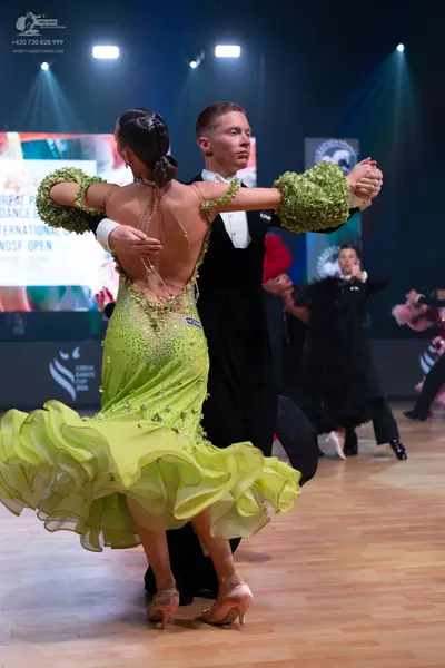 Dancesport competitor: Female dancer: lime green Latin dress with a multi-layered ruffled skirt, puffy 