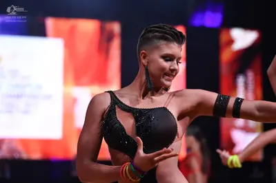 Dancesport competitor: Female dancer: black latin-style top with sequins and cutouts, large dark dangli