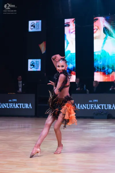Dancesport competitor: Female dancer: dark brown and orange Latin dress with fringe and layered fabric