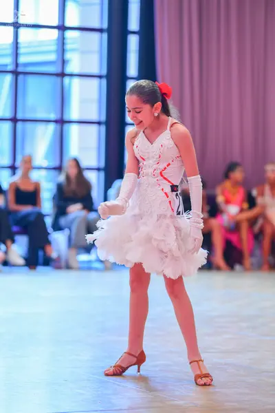 Dancesport competitor: Female dancer: white latin dress with red/pink lace details and a voluminous whi