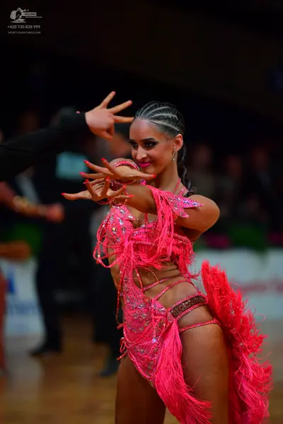 Dancesport competitor: Female dancer: bright pink Latin dance costume featuring extensive fringe, sequi