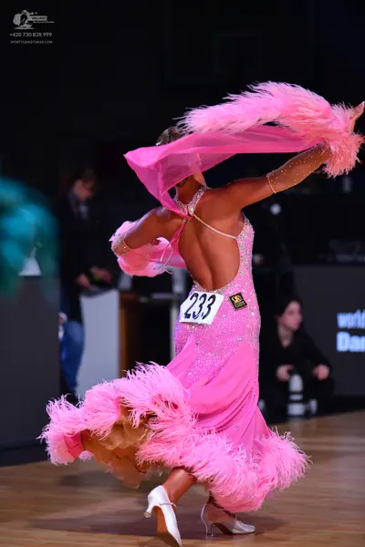 Dancesport competitor: Female dancer: pink latin dress with rhinestones and large pink feather trim
