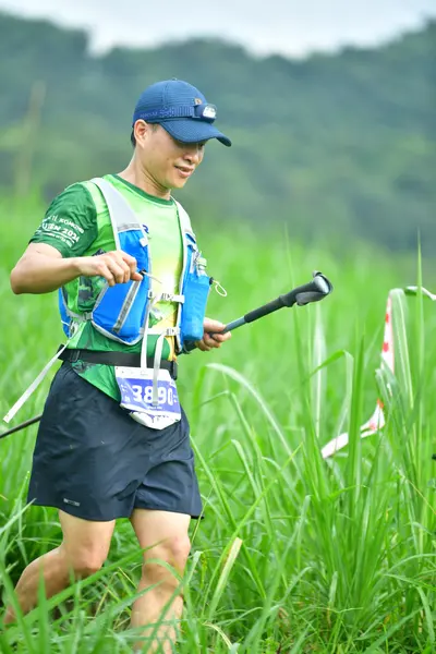 Marathon runner #3896: Runner 1: green, white, and blue patterned jersey, black shorts, blue cap, and a