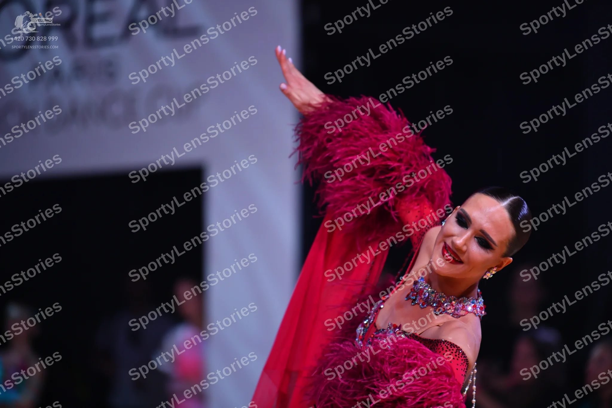Dancesport competitor: Main dancer: red Latin dress with large feather or faux fur embellishments on th
