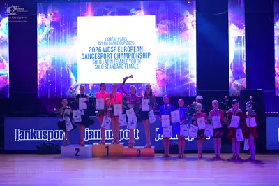 Dancesport competitor: Female dancers wearing bright pink/magenta dresses, black dresses, blue/teal dre