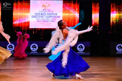 Dancesport competitor: Female dancer: royal blue ballgown with a voluminous skirt, featuring a white fe