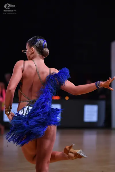Dancesport competitor: Female dancer: blue latin dress with gold sequin trim, featuring voluminous blue