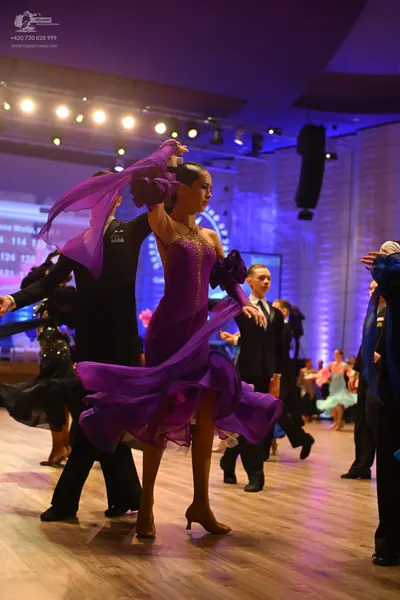 Dancesport competitor: Main female dancer: purple ballroom dress with a flowing chiffon skirt and volum