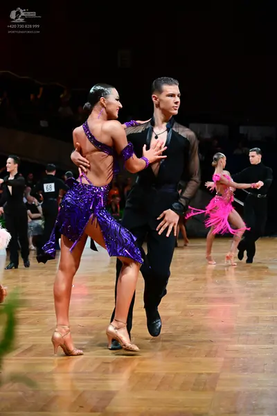 Dancesport competitor #68: Primary female dancer: purple sequined Latin dress with thin straps and an open 