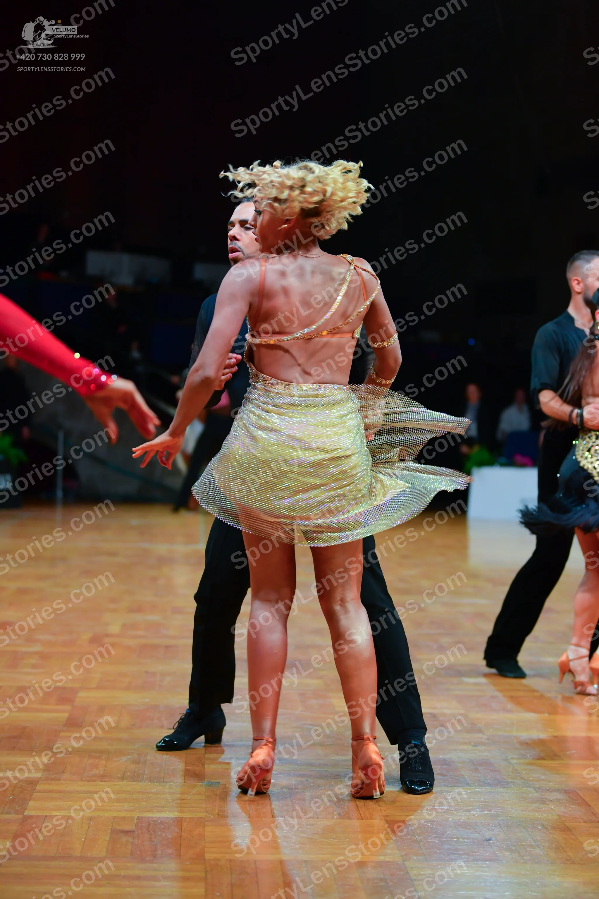Dancesport competitor: Main female dancer: yellow/gold sequined Latin dress with thin straps and a flar