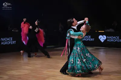 Dancesport competitor: Left female dancer: black Latin dance dress with voluminous pink feather or frin