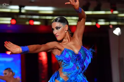 Dancesport competitor: Female dancer in foreground: blue latin dress with feathers, sequins, and cutout